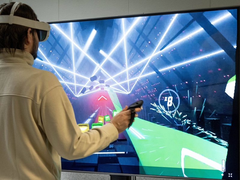 A player in a VR headset reaching out mid-game under blue arena lights